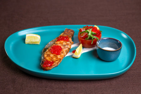 salmon steak with caviar on a blue plate.の写真素材