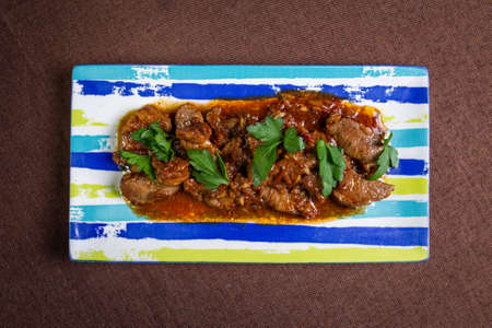 beef with sauce with herbs on a striped plate top viewの写真素材