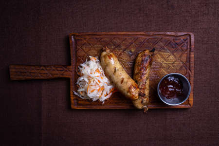 grilled homemade sausages with salted cabbage on the boardの写真素材