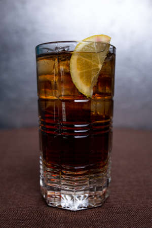 Cold lemonade with lemon and ice in a glass.