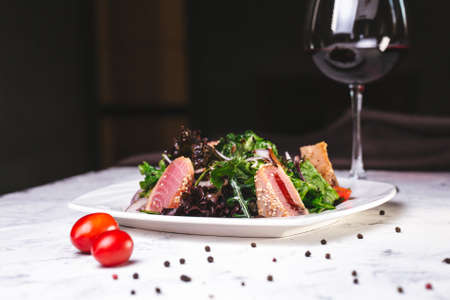 close-up fish salad with greens on a white plate.の写真素材