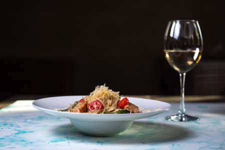 Pasta with hard cheese and meat with wine in the backgroundの写真素材