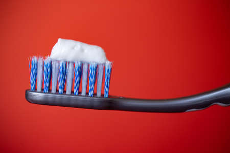 toothbrush with blue bristles and toothpaste on a red background.の写真素材