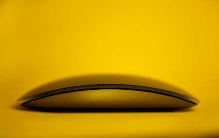 Modern tech wireless computer mouse on a yellow backgroundの写真素材