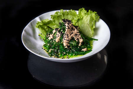 Japanese salad in a white plate on a black background. photos for menu designの写真素材