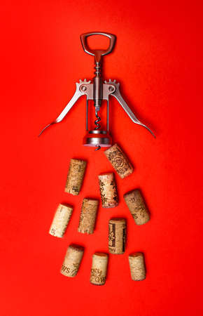corkscrew for wine and corks on a red background.の写真素材