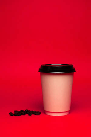 paper cup of coffee with beans on a red backgroundの写真素材