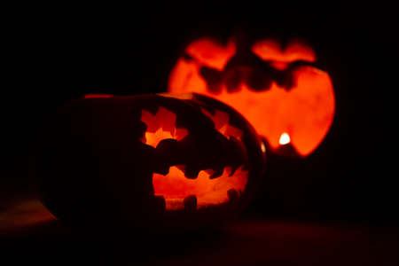 carved pumpkin faces for halloween. pumpkins glow on a black backgroundの写真素材