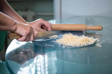 An unrecognizable woman cuts noodles. womens hands close-up