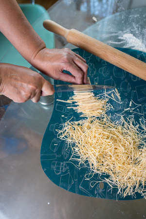 a woman cuts homemade noodles in the kitchenの写真素材
