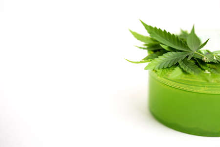 a cannabis leaf and a green jar on a white background. Copy space.の写真素材