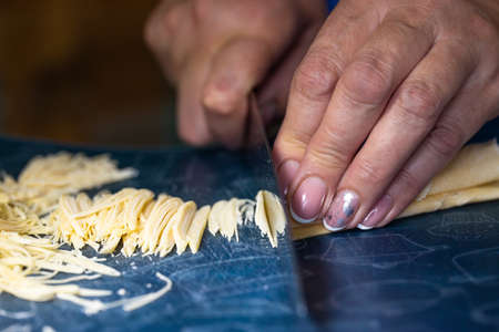 a woman cuts homemade noodles in the kitchen.の写真素材