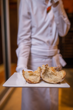 the waiter holds a crusty bread on a plate.の写真素材