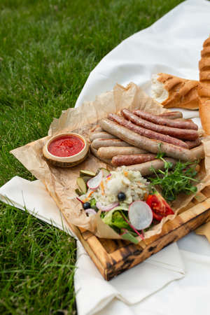 homemade grilled sausages with vegetables and wine on a picnic.