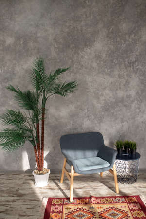 designer textured gray wall in the interior with an armchair and an artificial flower.の写真素材