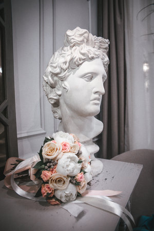 white plaster statue of a woman's head and a bouquet of flowers.の写真素材