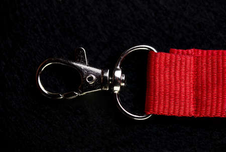 metal carabiner on a red ribbon on a black background.