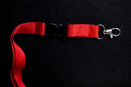 metal carabiner on a red ribbon on a black backgroundの写真素材