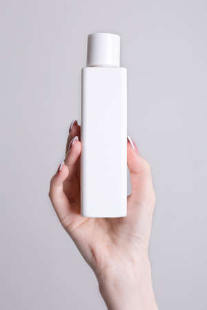 white bottle for cosmetics in a woman's hand.