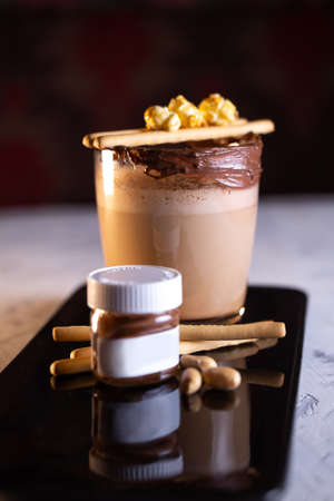 Coffee with a jar of chocolate paste and cookies on a black plateの写真素材