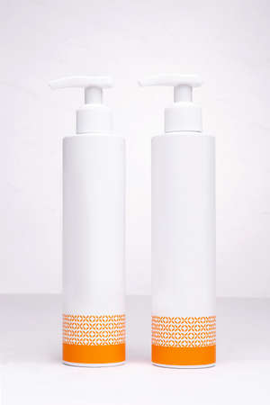 two white bottles for cosmetics with an orange pattern on a white background.