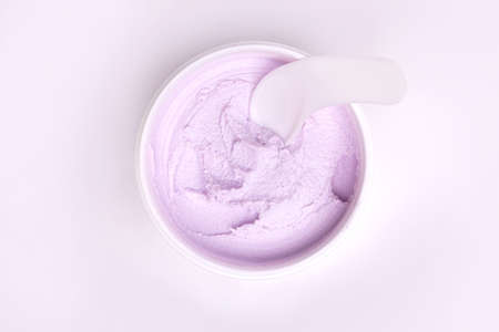 top view of a white jar of pink with a gentle face cream on a white background.