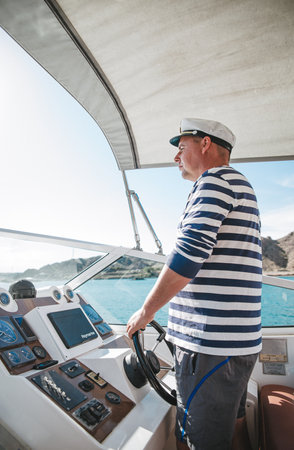 Almaty. Kazakhstan 26.05.2020 the captain of the yacht at the helm controls the boat on the water.のeditorial素材