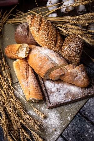 Freshly baked crusty bread and buns with wheat ears top view.の写真素材
