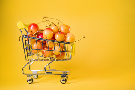 supermarket trolley with yellow cherries on a yellow background.の写真素材