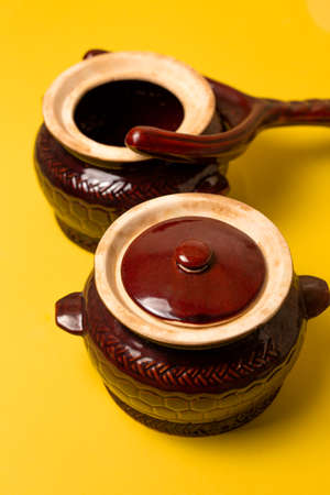 clay pot for hot dishes and pot holder on a yellow background.