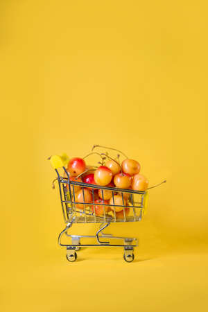 supermarket trolley with yellow cherries on a yellow background.の写真素材