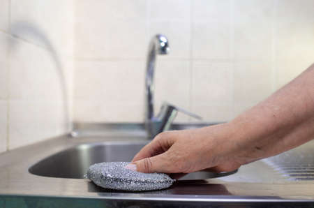 a woman's hand cleans the mixer on the sink in the kitchen