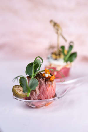 bruschetta a piece of stewed beef on a plastic spoon.