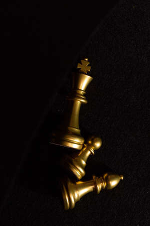 golden chess pieces lie on a black background top view.