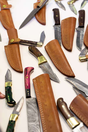 different knives and leather cases on a white background.