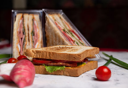 juicy crispy sandwich with ham and vegetables close-up on the board.の写真素材