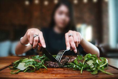 a girl eats a steak close-up in a restaurantの写真素材