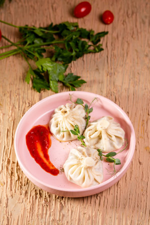 three khinkali with red sauce on a plate in a restaurant
