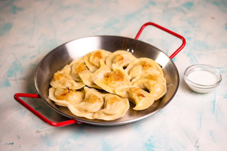 dumplings with potatoes and sour cream in a frying pan.の写真素材