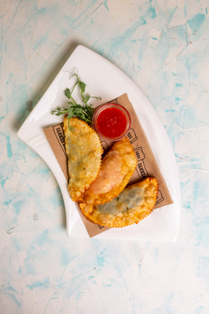 top view of delicious pasties with sauce on a white plate.