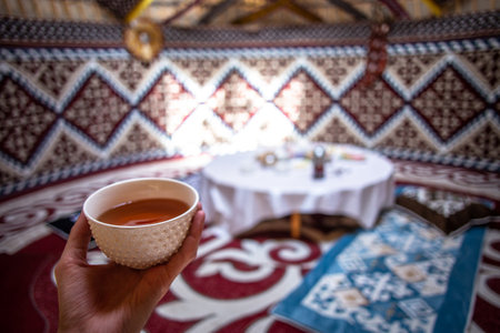 a cup of tea in a man's hand behind a dastarkhan in the Kazakh national yurt.の写真素材