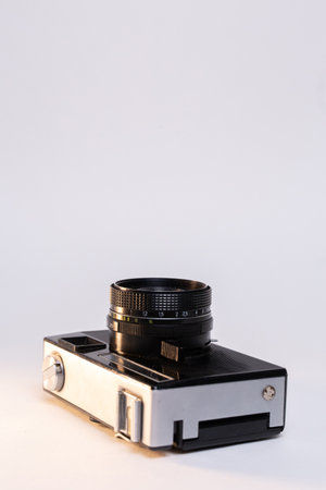 Vintage film camera with a sleek silver body and a classic black manual focus lens, elegantly...