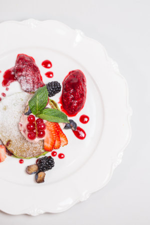 Delicious and healthy breakfast with pancakes, fruits, and berries on white plate. Isolated. Healthy eating concept.の写真素材