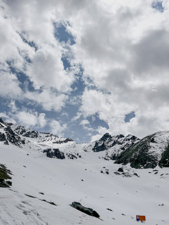 Stunning view of snow-capped mountains under blue sky and clouds. Ideal for travel brochure or...