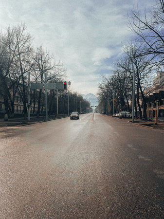 Empty city street with trees, distant mountains, and blue skyの写真素材