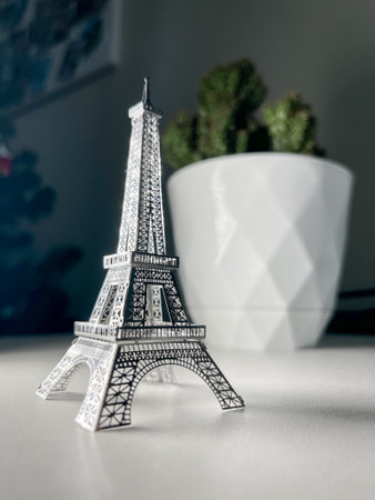 An isolated silver Eiffel Tower model on a white background with a blurred background of a cactus in a white pot.の写真素材