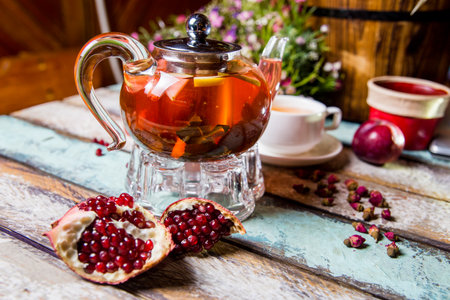 red fruit tea in a teapot with pomegranate on the table.の写真素材