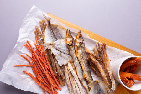A variety of dehydrated fish, carrots, and pumpkin slices on a white paper over gray background....