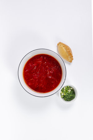 An appetizing portion of rich red borscht garnished with fresh herbs and spicy pies.