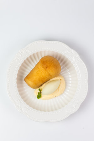 Elegant serving of Neapolitan rum baba dessert with creamy custard and refreshing sorbet on a white...